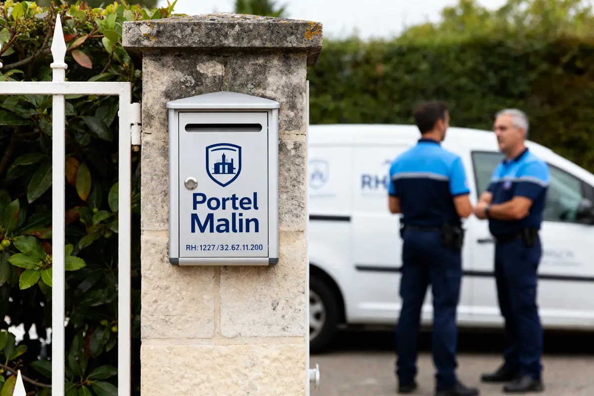 Boîte aux lettres Portail Malin sur un mur avec agents de sécurité en arrière-plan