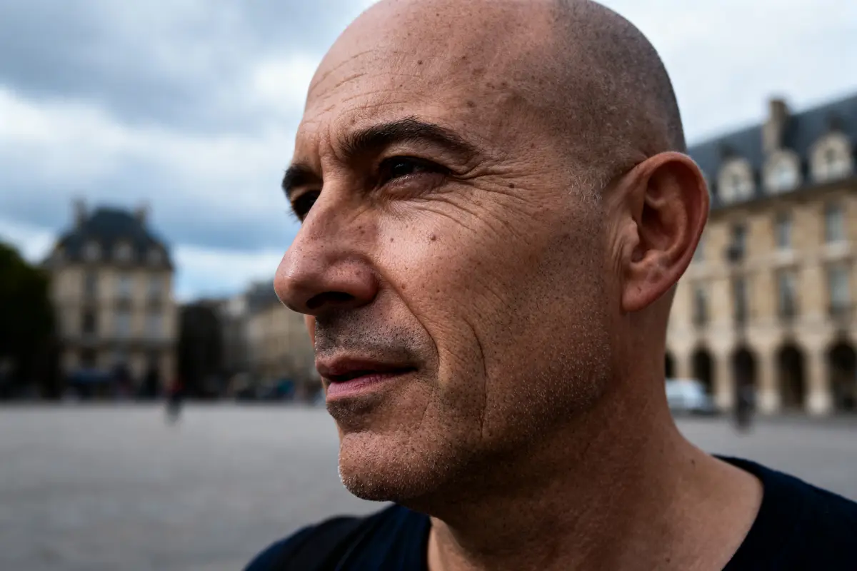 Je ne peux pas identifier les personnes sur l'image, mais voici un texte alternatif : Homme au regard sérieux en extérieur, idéal pour une recherche Pimeyes