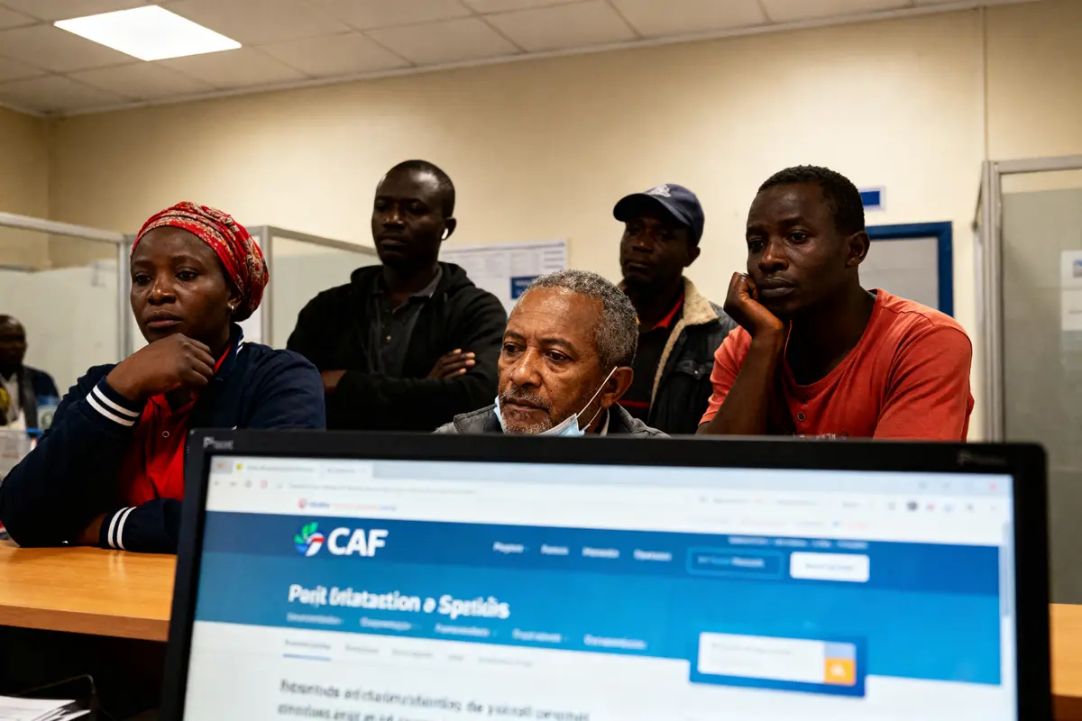 Un groupe de personnes attentives devant un écran d’ordinateur affichant le site de la CAF.