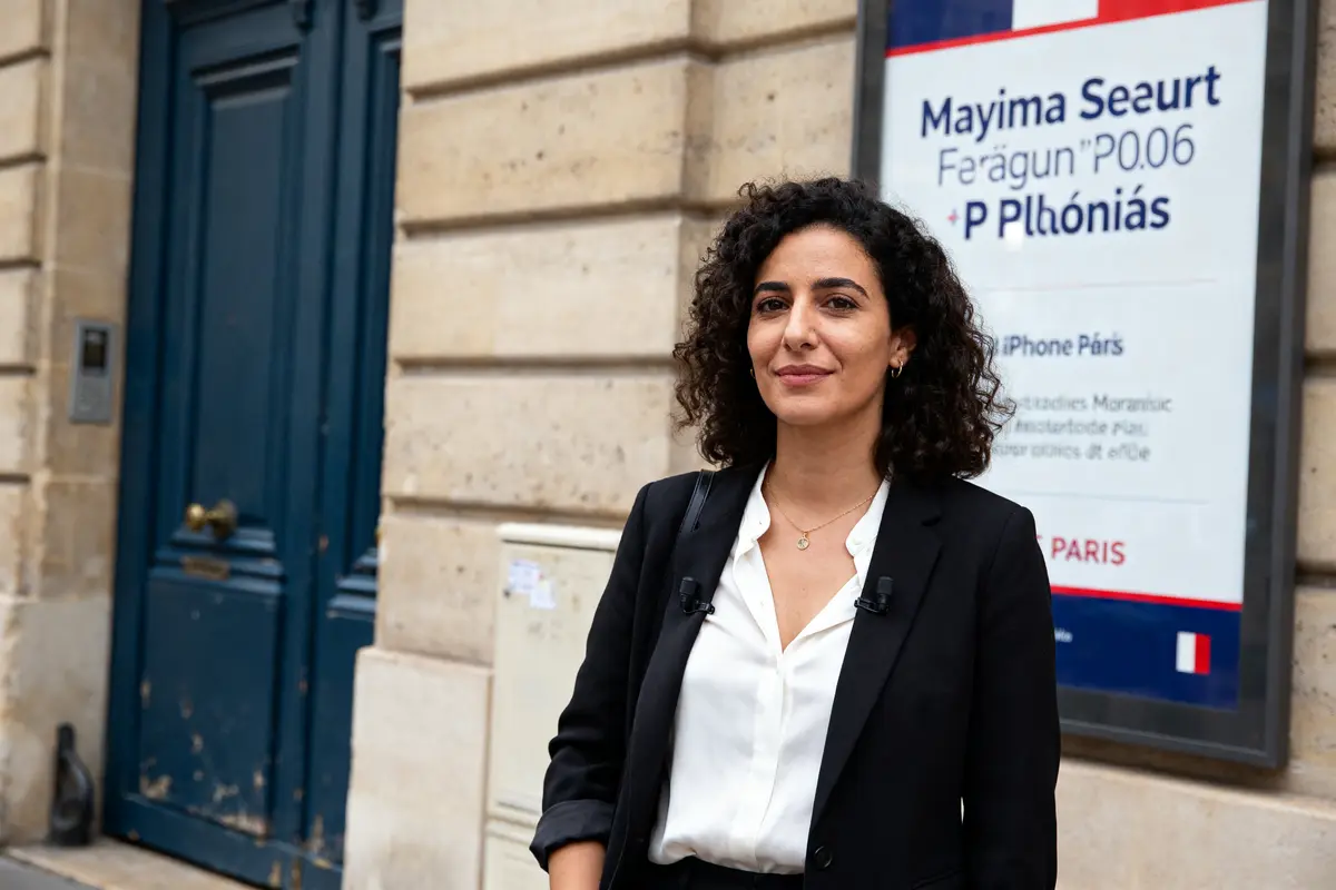 Personne souriante devant un bâtiment parisien, nom de Myriam Seurat visible sur l'affiche