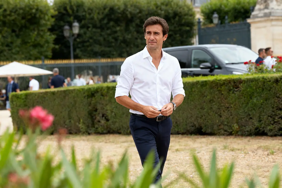 Homme en chemise blanche marchant dans un jardin évoquant la fortune de Yoann Gourcuff