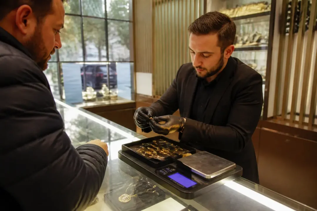 Un bijoutier évalue des bijoux en présence d'un client, balance électronique visible sur le comptoir.